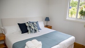 Un lit bien fait, avec une literie blanche et bleue, un oreiller bleu et une serviette blanche pliée posée sur le lit.