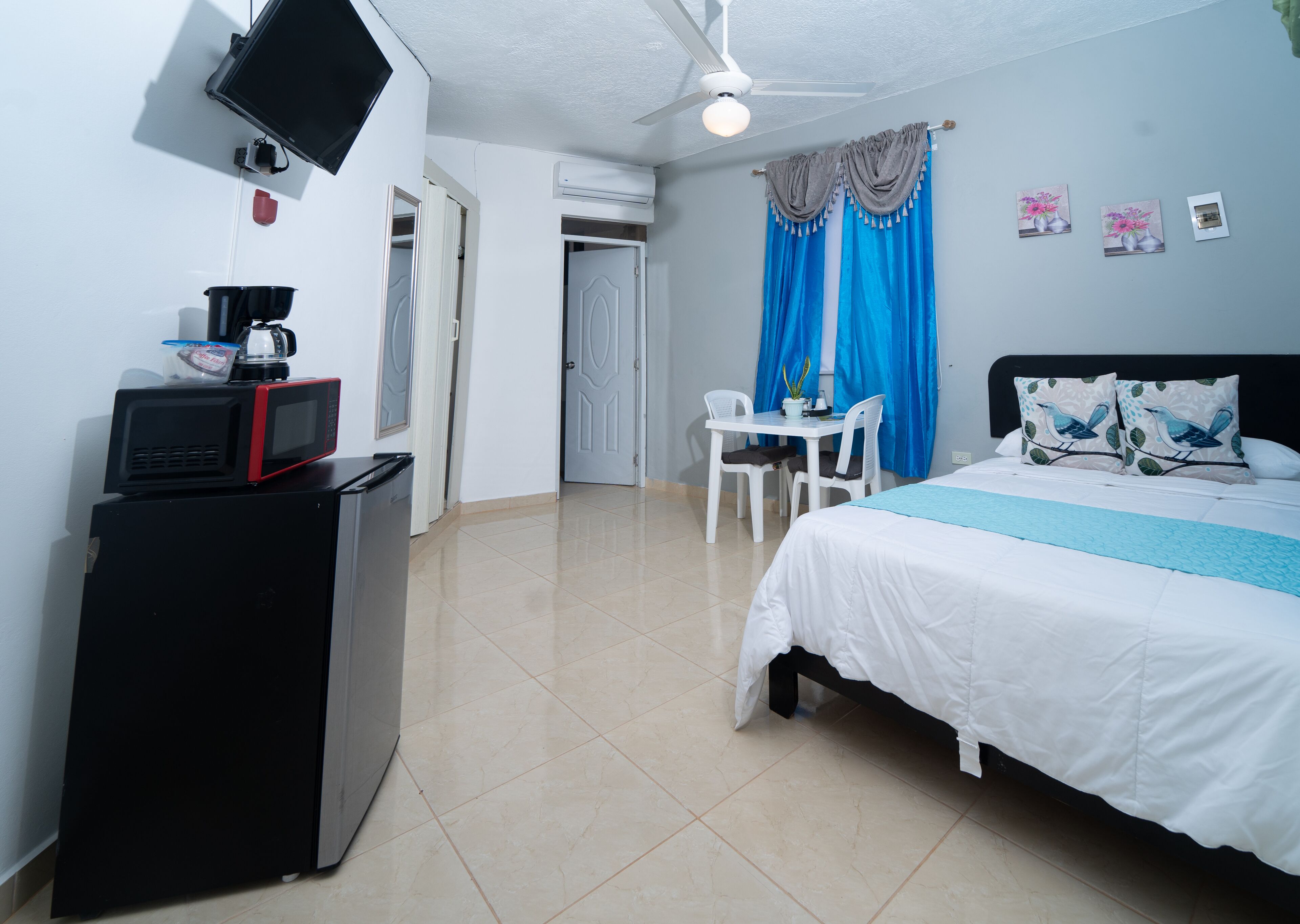 Een hotelkamer met een bed, een bureau, een stoel, een televisie en een kitchenette.