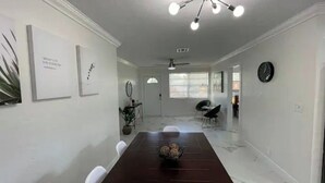 Un espace repas comprenant une longue table, des chaises, un ventilateur de plafond et des œuvres d’art accrochées au mur.