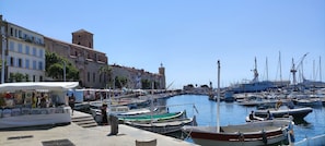 A marina with boats docked, a market area, and historic buildings.