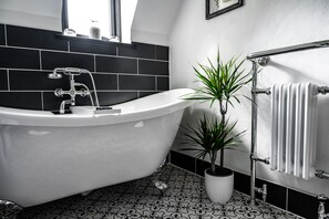 A modern bathroom with a freestanding bathtub, a radiator, and a potted plant. - White Rose Tower (Invergordon)
