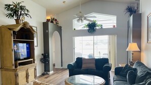 Ein Wohnzimmer mit Fernseher, zwei Sofas, einem Couchtisch und einer Zierpflanze.