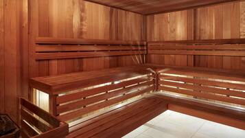 A sauna with wooden benches and walls, tiled floor, and a bench with a backrest.