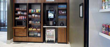 A Starbucks kiosk with a coffee machine, refrigerated display, and shelves stocked with snacks and beverages.