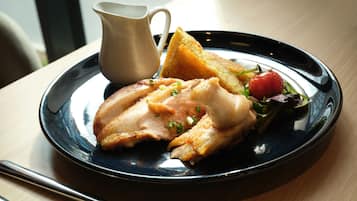 Une assiette avec de la nourriture, une tasse et une fourchette sur une table.
