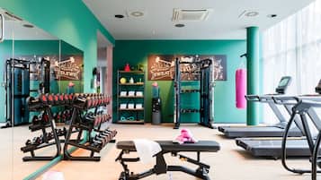 Ein Fitnessraum mit Gewichthebersportgeräten, Laufbändern und einer Bank.