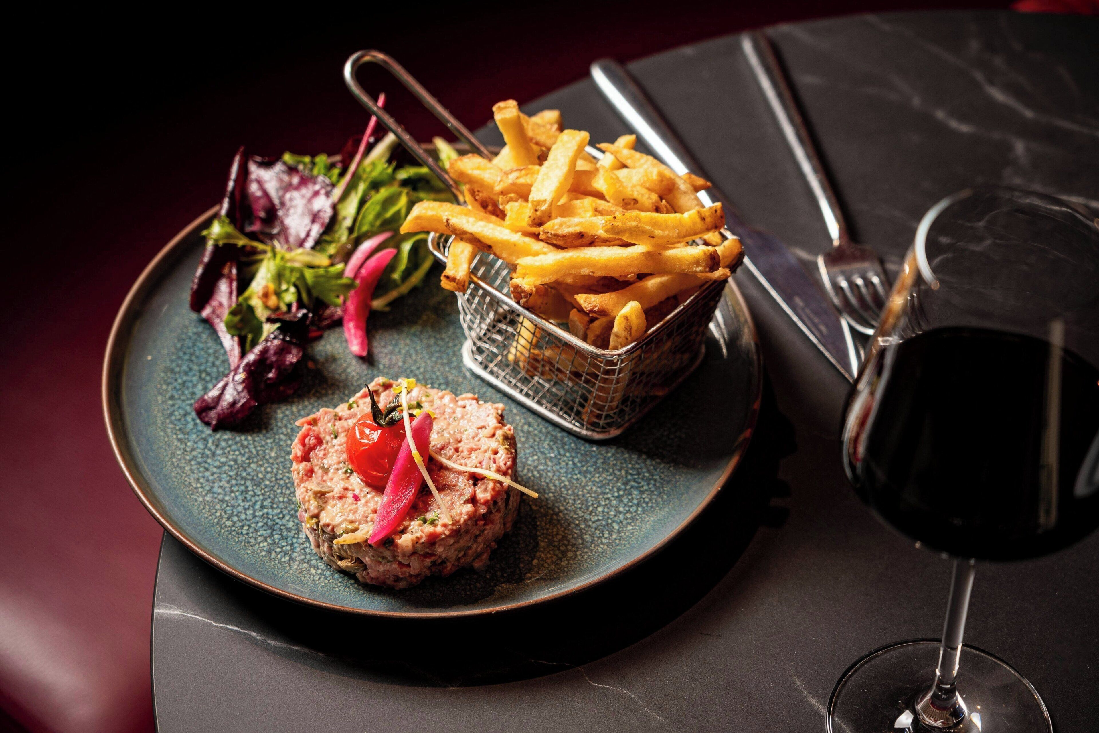 A plate with a meat patty, fries, and a salad.