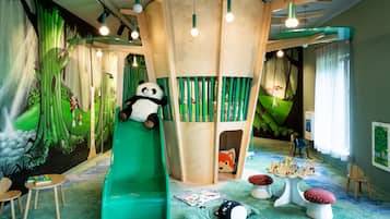 Ein Spielbereich für Kinder mit Rutsche, Spielhaus und verschiedenen Spielsachen.