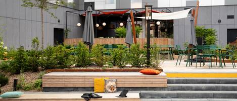A modern outdoor seating area with wooden steps, green chairs, and umbrellas.