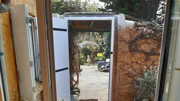 A doorway leading to an outdoor area with a tiled floor, a metal mat at the entrance, and potted plants. - Atypical house 15 minutes from Carcassonne (PEZENS)