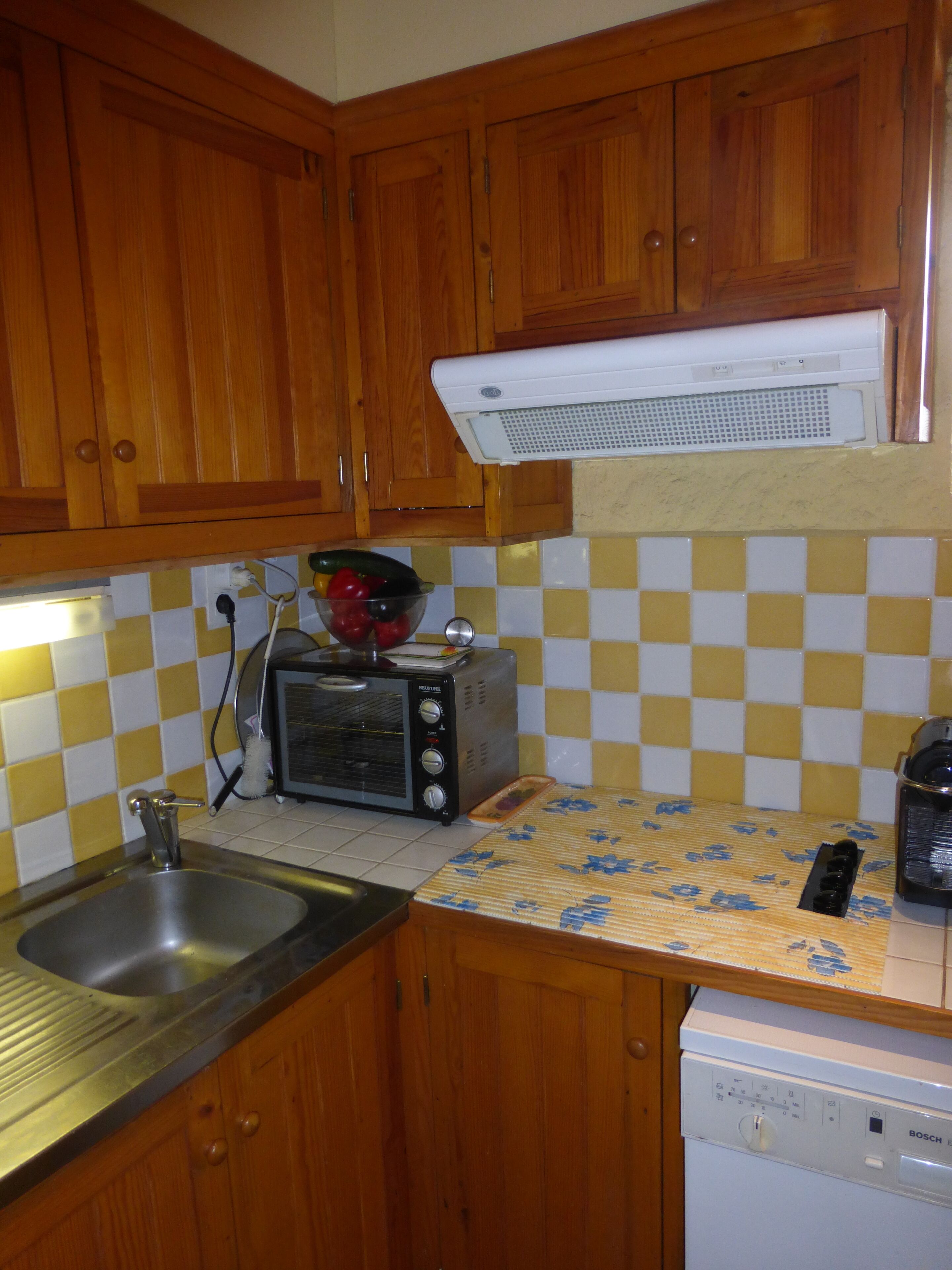 Een keuken met houten kastjes, een broodrooster, een spoelbak en een vaatwasser.