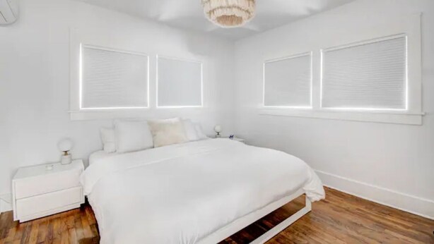 Un dormitorio con una cama grande, paredes blancas y una araña.
