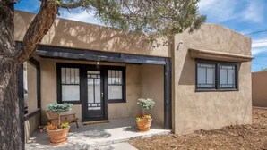 Una casa moderna con techo plano, un porche cubierto y dos ventanas grandes.