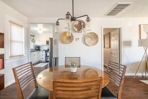 Enjoy meals in this cozy dining area with a round table and four chairs, surrounded by decorative plates and a potted plant.