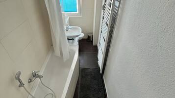 Een bad/douchecombinatie, een haardroger, handdoeken, zeep