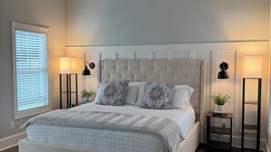 A bedroom with a large bed, two bedside tables, a window with blinds, and a ceiling with a sloped design. - New Country Cottage, 3BR 2.5 BA, Ensuite Master on Main, Relax Rewind Repeat (High Point)