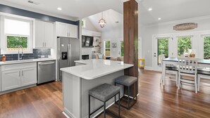 A spacious kitchen with a central island, white cabinetry, and a wooden accent wall. - New Country Cottage, 3BR 2.5 BA, Ensuite Master on Main, Relax Rewind Repeat (High Point)