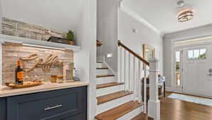 A modern kitchen with a wooden countertop, a coffee-themed backsplash, and a staircase with white railings. - New Country Cottage, 3BR 2.5 BA, Ensuite Master on Main, Relax Rewind Repeat (High Point)