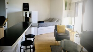 A compact living space with a kitchenette, a bed, a dining area, and a small seating area. - Grand Studio Avec Terrasse et vue mer (Saint-Laurent-du-Var)