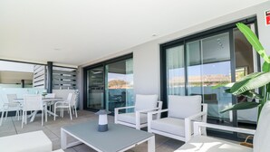 Ein moderner Außenbereich mit weißer Möbel, eine Glastür, die auf einen Balkon führt, und Blick auf die Stadt.