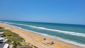 Una playa con cielo despejado, orilla arenosa y algunas personas y sombrillas.