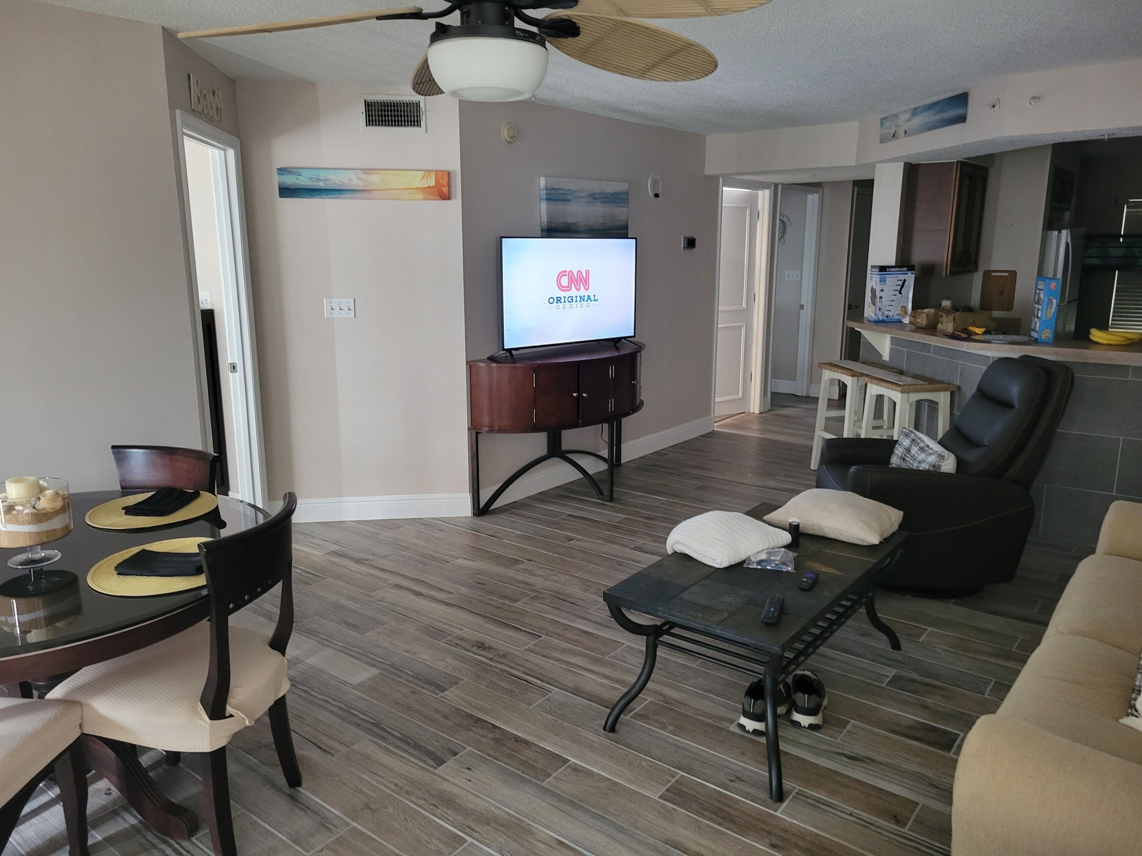 Una sala de estar moderna con comedor, televisor de pantalla plana y zona de cocina.