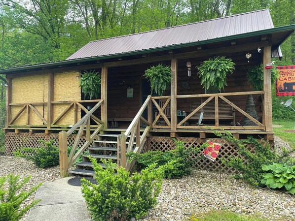 A rustic cabin with a wooden exterior, a porch with steps, and a sign that reads "WELCOME". - Welcome to our peaceful, rustic cabin in the Hocking Hills Area (Wellston)