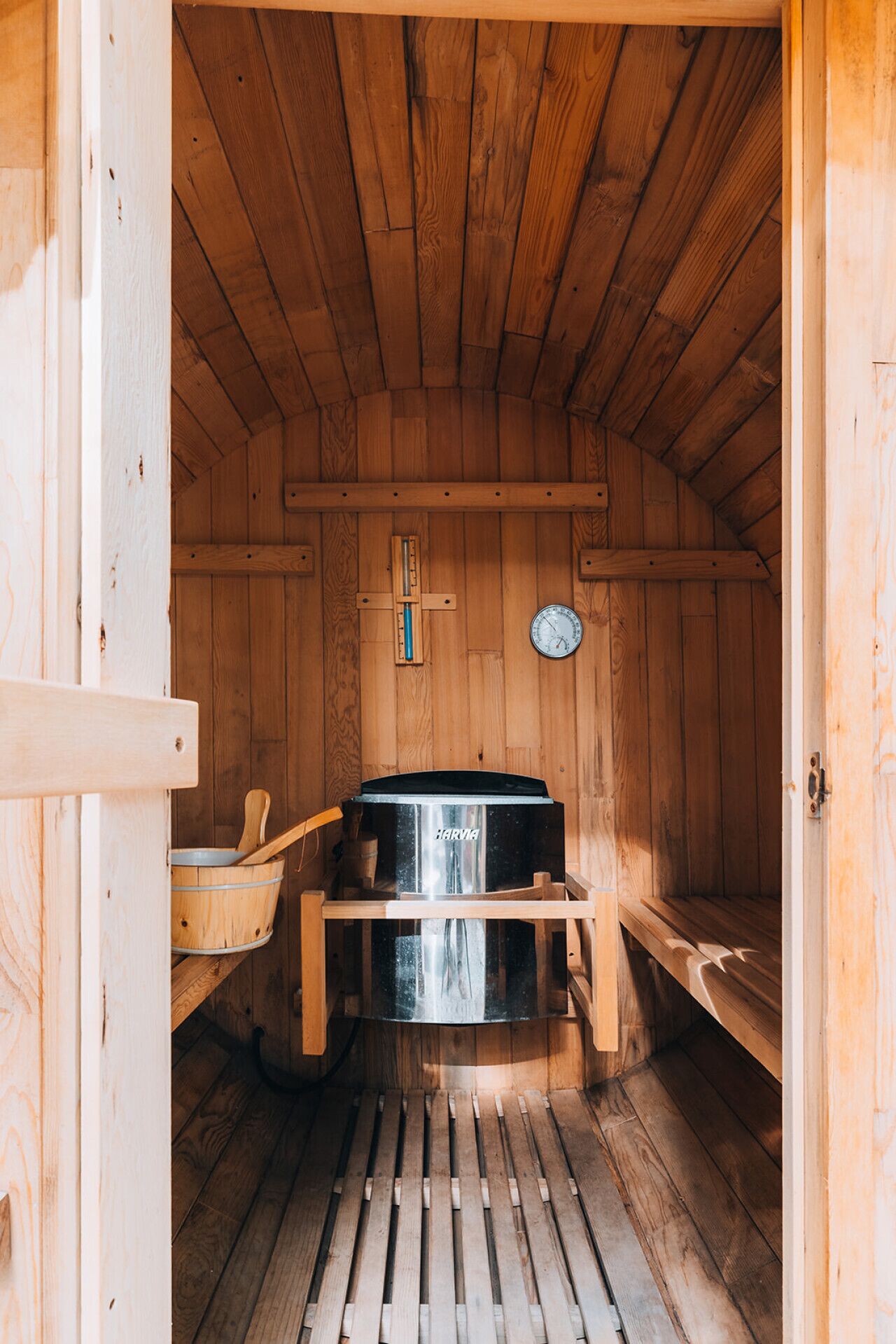Una sauna con pareti in legno e soffitto spiovente, con al centro una stanza per il bagno turco e una panca di legno.
