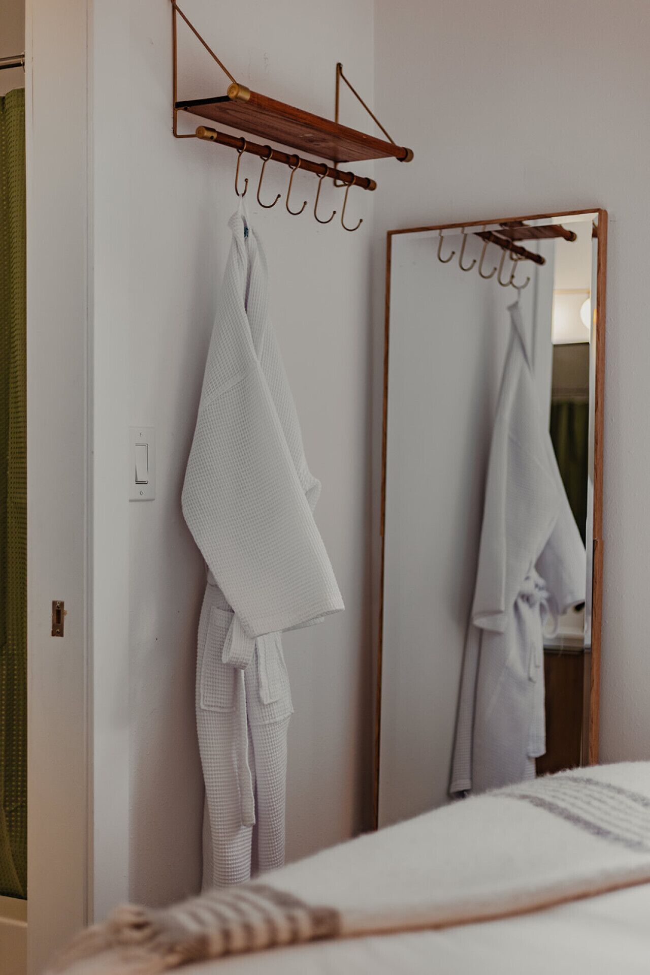 A bathroom with a large mirror, a towel rack, and a towel hanging on it.