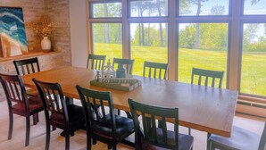 A dining room with a large table, six chairs, a painting, and a vase with flowers.