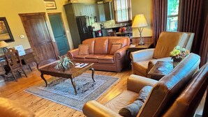 A living room with leather sofas, a coffee table, a rug, and a lamp. - Beautiful Cabin - Secluded But Convenient (Branson)