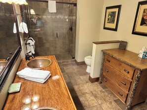 A bathroom with a wooden vanity, a large mirror, a sink, a toilet, and a shower area.