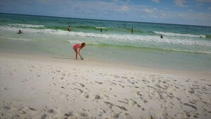 Ein Strand mit Fußspuren im Sand und Menschen im Wasser.