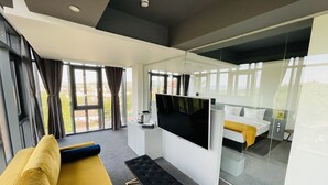 Une chambre d’hôtel moderne dotée d’une grande fenêtre, d’un téléviseur à écran plat, d’un canapé et d’un lit.