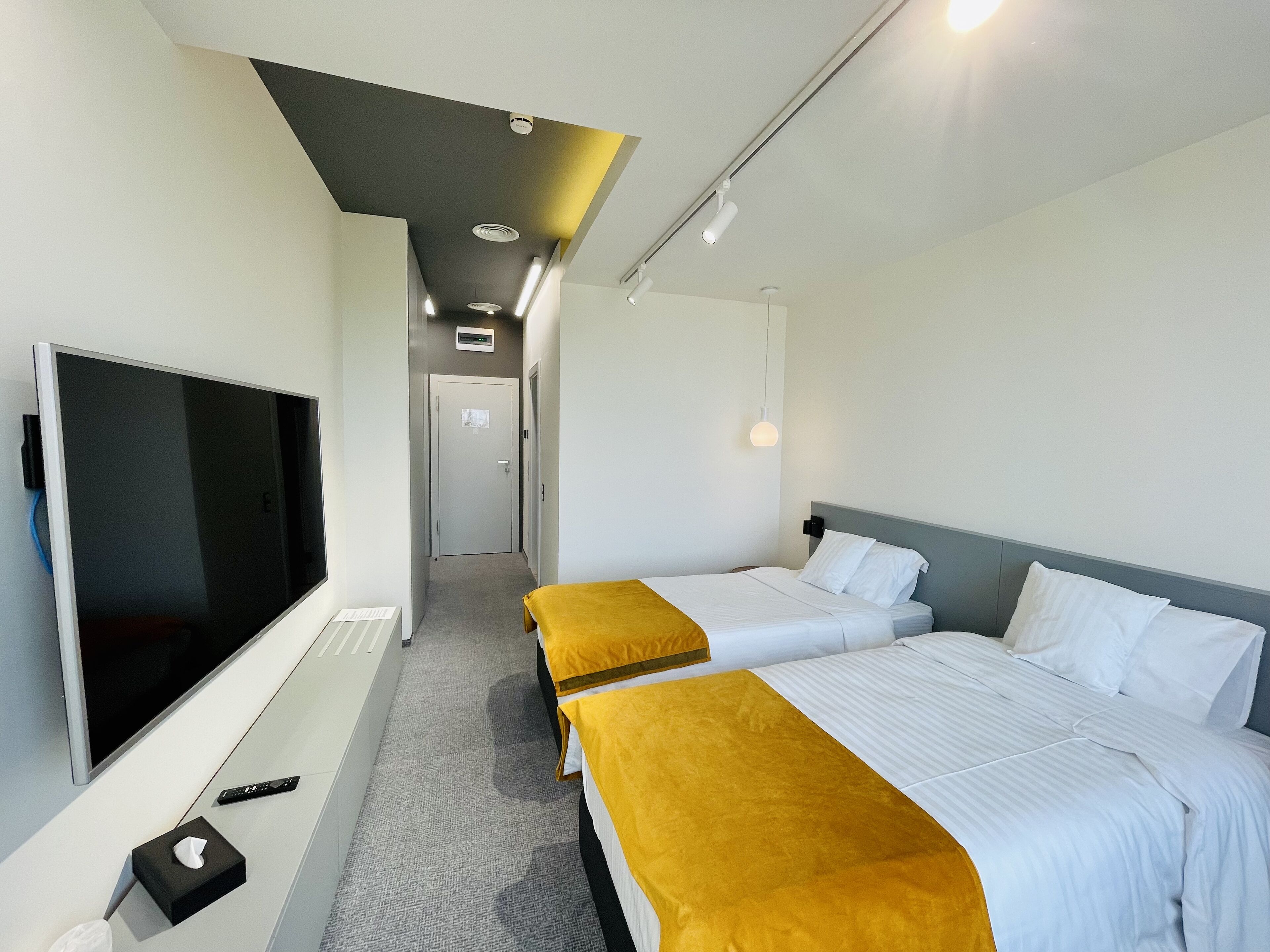 A hotel room with two beds, a TV, and a remote control on the floor.
