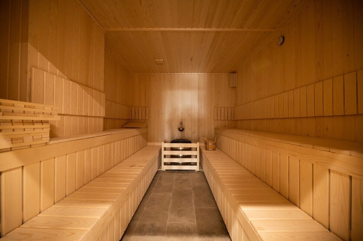 Eine Sauna mit Holzbänken, die in einer Mittelgang angeordnet sind.