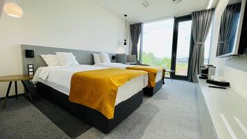 A modern hotel room with two beds, a desk, and a TV.