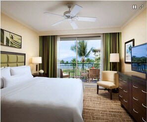 Relax in this inviting room with a large bed, ceiling fan, and balcony view.
