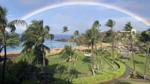 A tropical resort with a view of the ocean, palm trees, and a rainbow. - Amazing ocean front studio on the beach at Westin Kaanapali north. (Lahaina)