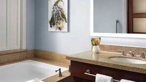 A modern bathroom with a bathtub, two sinks, a large mirror, and a framed artwork on the wall. - Amazing ocean front studio on the beach at Westin Kaanapali north. (Lahaina)