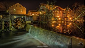 Un bâtiment historique doté d’une grande roue à eau et abritant un restaurant appelé « Le Vieux Moulin », ouvert le soir.