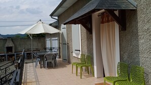 Eine Terrasse mit Tisch und Stühlen, ein überdachter Bereich und Blick zum Himmel.