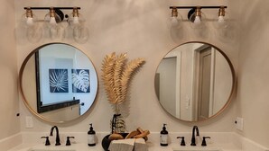 A bathroom with two round mirrors, a white sink, and wooden cabinets. - “Lake Escape”- Lake House @ Lake of Arbuckle’s (Sulphur)