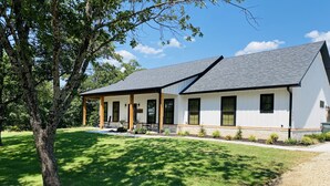 A two-story building with a covered porch and a gravel driveway. - “Lake Escape”- Lake House @ Lake of Arbuckle’s (Sulphur)