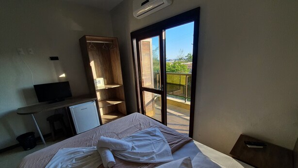 A hotel room with a bed, a desk, a TV, a wardrobe, and a balcony with a view.