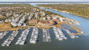 Une vue aérienne d’une marina où sont amarrés de nombreux bateaux, entourée de bâtiments résidentiels et avec un pont en arrière-plan.