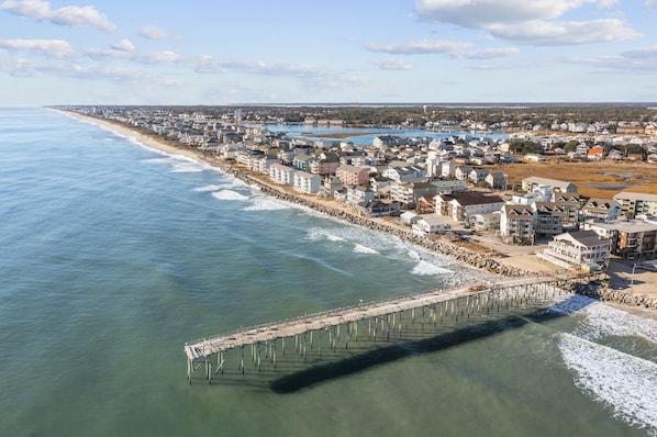 Une ville côtière dotée d’une jetée qui s’avance dans la mer, entourée d’immeubles résidentiels et bordée d’une plage.