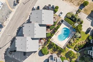 Vue aérienne d’un hôtel comprenant plusieurs bâtiments, une piscine et des jardins aménagés.