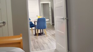 Une chambre à coucher avec un lit et une porte donnant sur un coin repas équipé d’une table et de chaises.