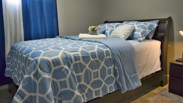 Un dormitorio con cama, mesita de noche y mesilla auxiliar.